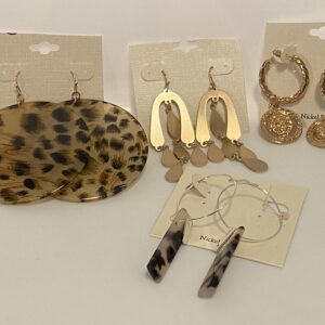 A variety of '23 Christmas In July Gold & Muted Animal Prints earrings and necklaces on a white table.