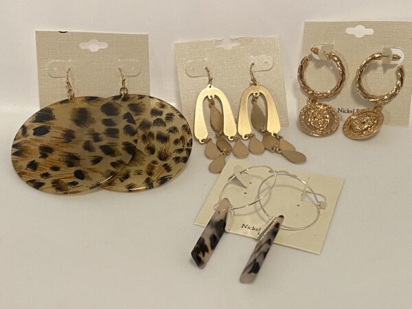 A variety of '23 Christmas In July Gold & Muted Animal Prints earrings and necklaces on a white table.